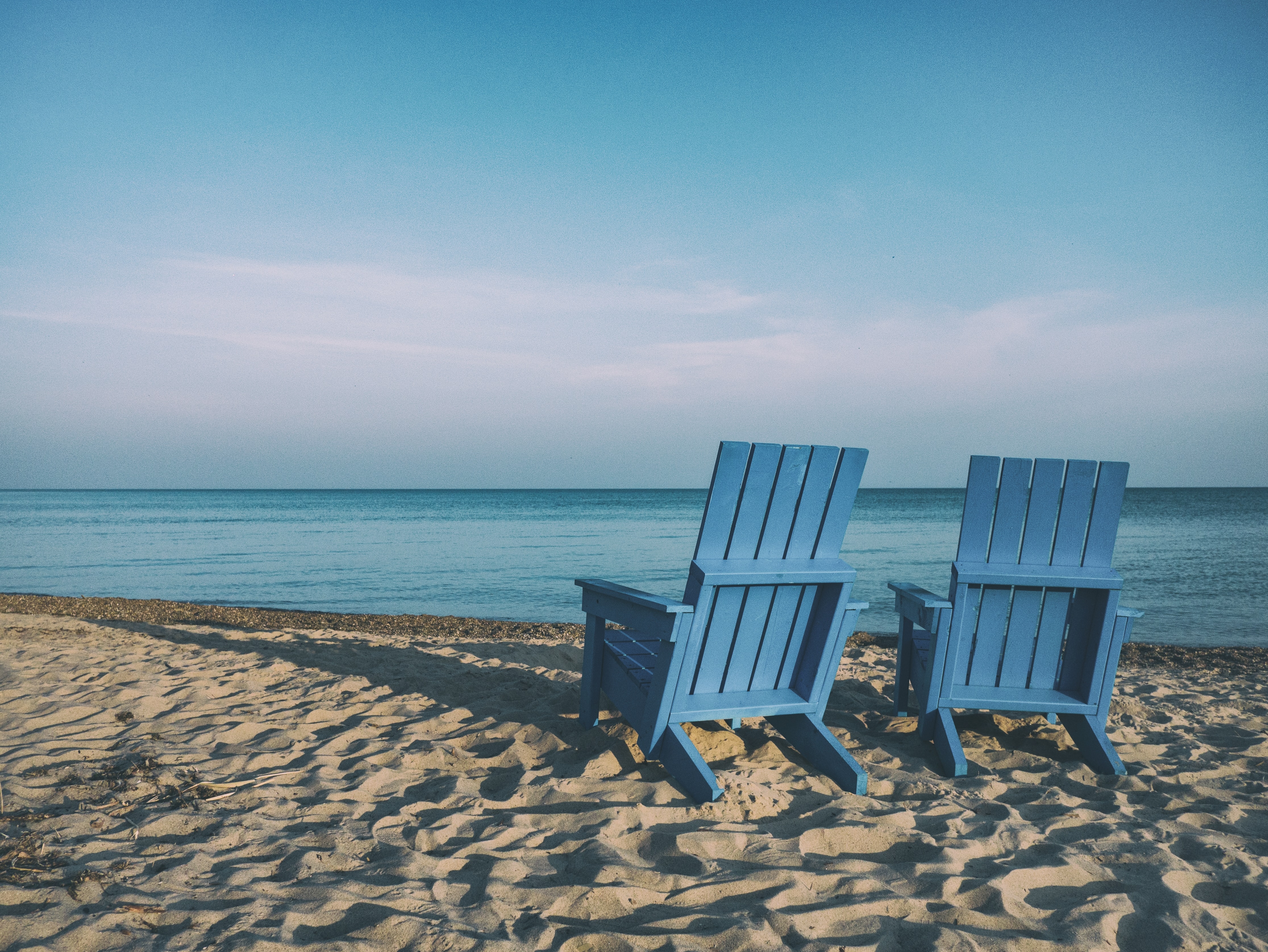 2 sedie di legno blu sulla riva del mare al tramonto