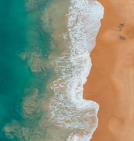 Onde del mare viste dall’alto si infrangono sulla sabbia 