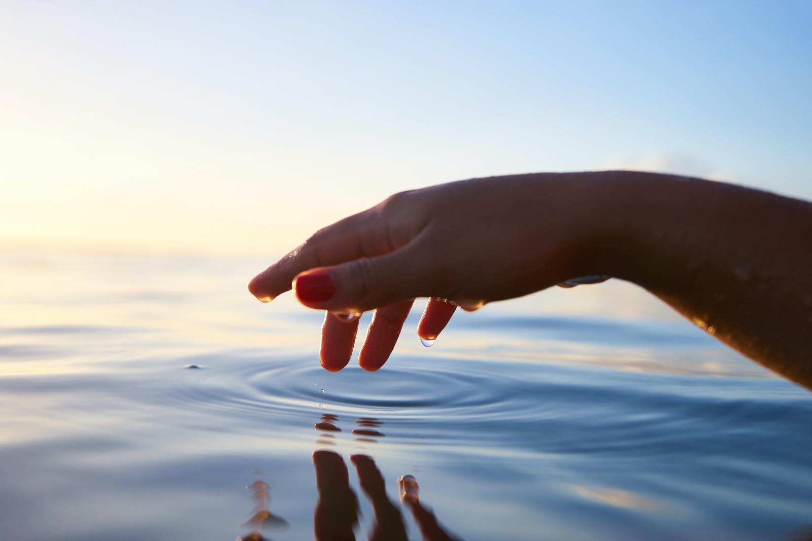 Scopri le 8 mosse che permettono un notevole risparmio idrico Mano di donna che sfiora superficie di acqua