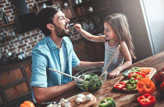 Una bambina che cucina e gioca con il suo papà