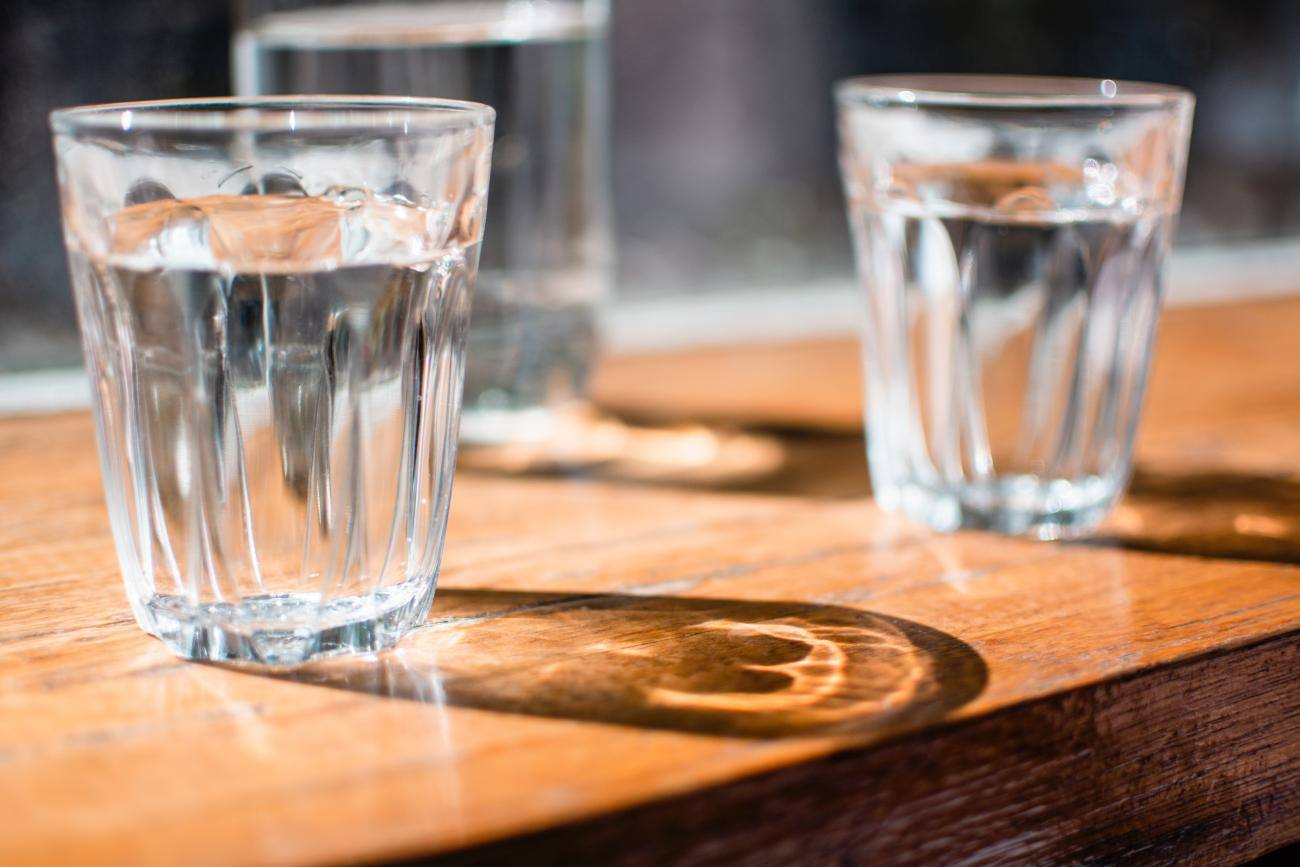 Bicchieri di vetro pieni di acqua su tavolo di legno
