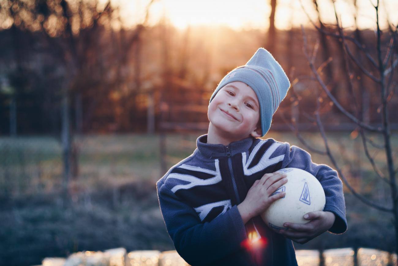 Bambino che gioca a pallone in autunno
