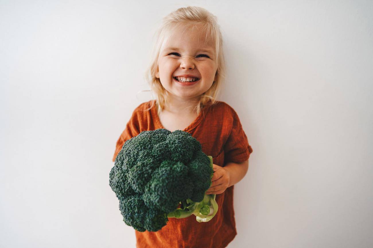 Bambina sorridente con broccoli