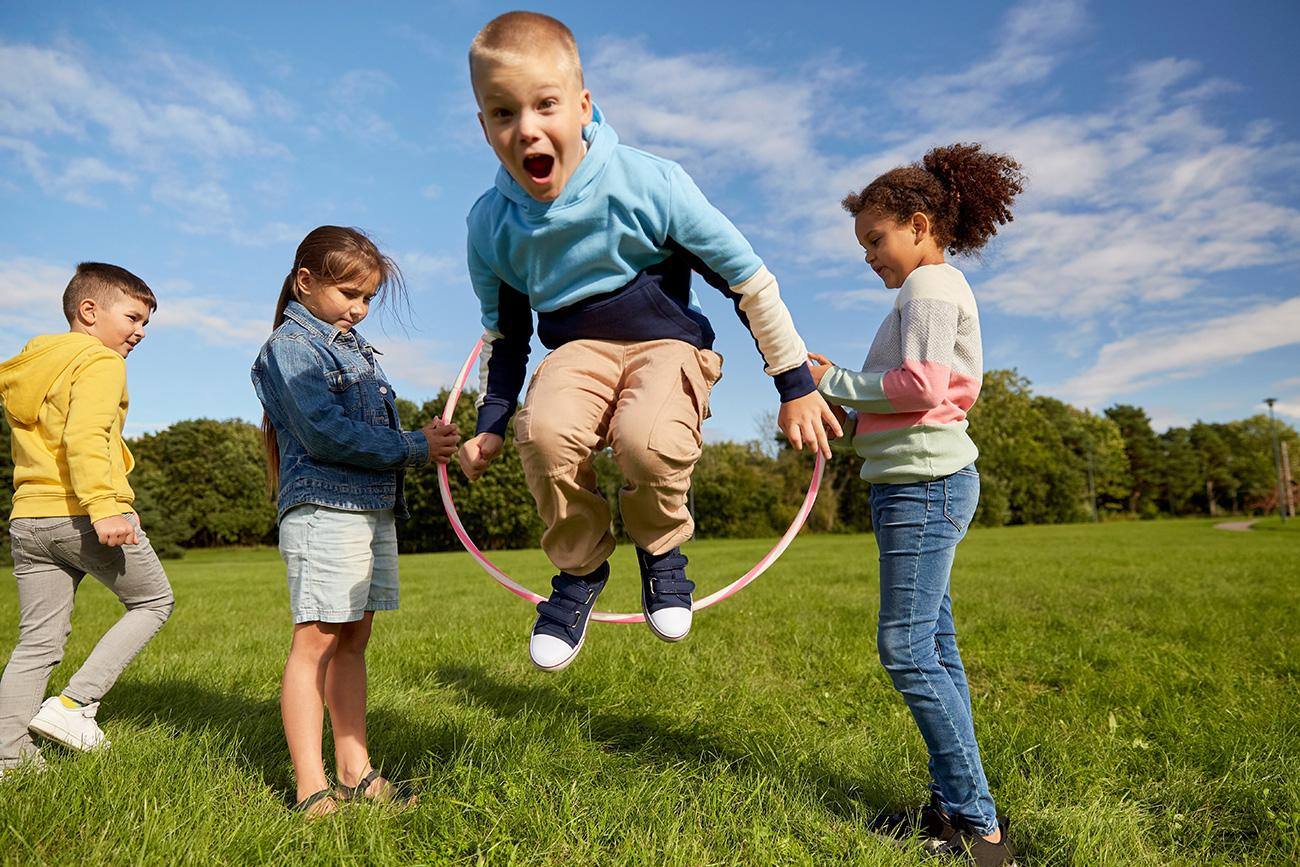 Bambini che giocano con un hula hoop sul prato