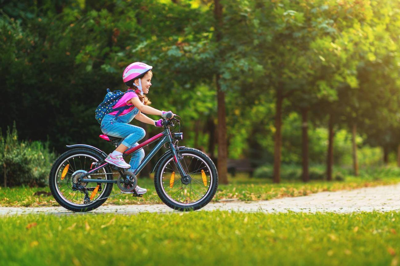 Bambina sorridente in bicicletta al parco