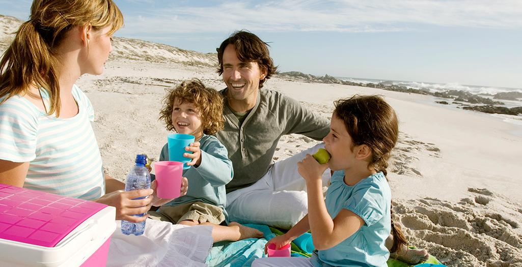 Famiglia con bimbi piccoli si reidrata in spiaggia