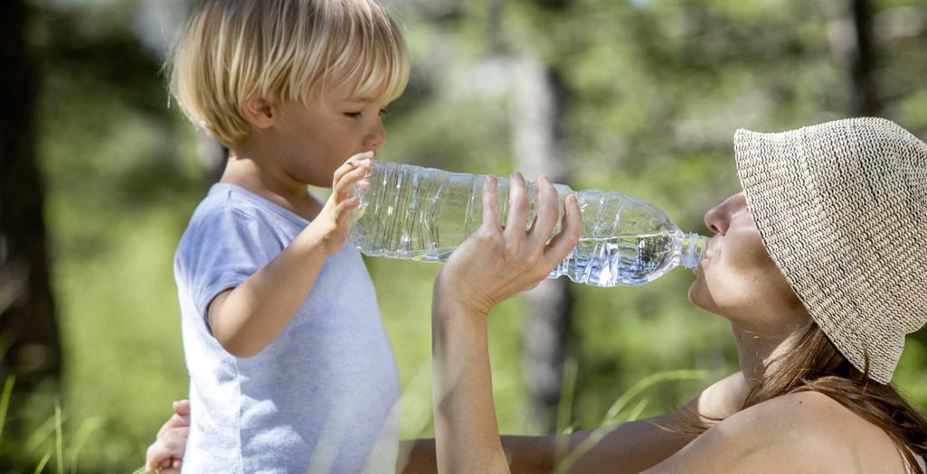Bambino piccolo e mamma bevono acqua dalla bottiglia