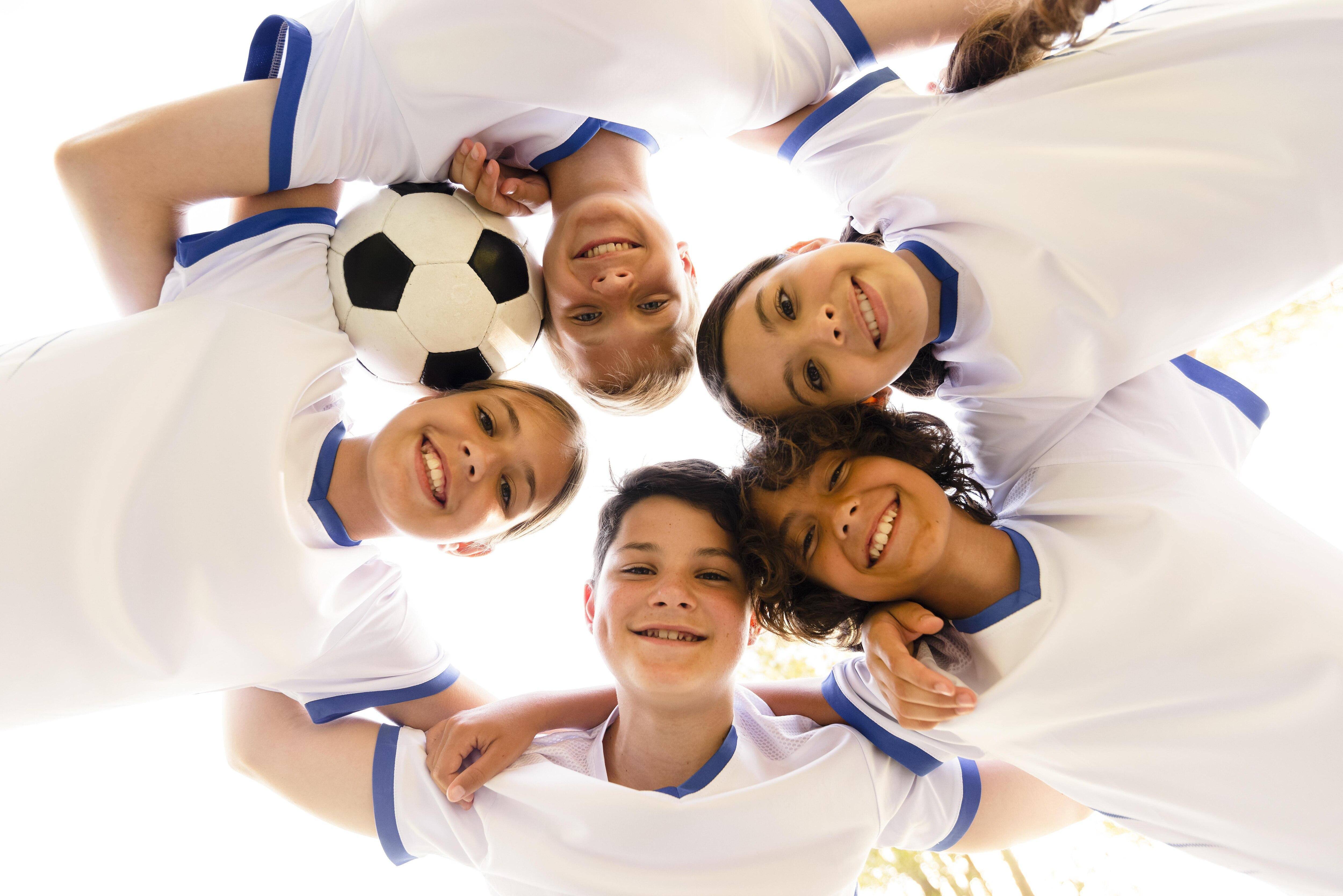 Bambini con pallone da calcio e maglietta bianca sorridono alla fotocamera