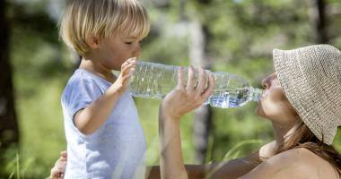 Bambino piccolo e mamma bevono acqua dalla bottiglia