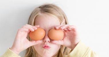 Una bambina che tiene due uova davanti agli occhi