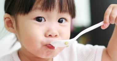 Una bambina che mangia un cucchiaio di cibo   Title immagine: Il pasto è importante!