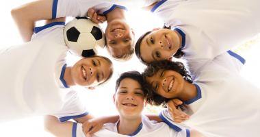 Bambini con pallone da calcio e maglietta bianca sorridono alla fotocamera 