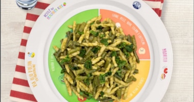 Foto dall’alto di pasta alla genovese Nutripiatto sul tavolo con bicchiere d’acqua accanto