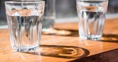 Bicchieri di vetro pieni di acqua su tavolo di legno 