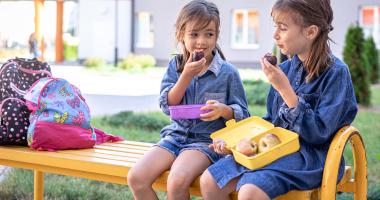Due bambine sedute su una panchina a fare una merenda sana e nutriente