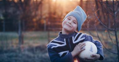 Bambino che gioca a pallone in autunno