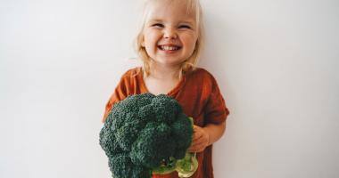 Bambina sorridente con broccoli