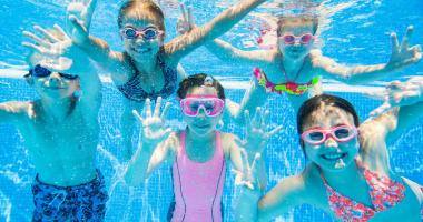 Gruppo di bambini sorridenti sott’acqua in piscina