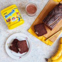 Piatto con banana bread al Nesquik, bicchiere con latte al nesquik e confezione di nesquik in polvere