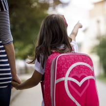 Bambina con zaino sulle spalle per mano alla mamma