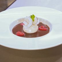Zuppa al cioccolato con scaglie di cocco e fragole in un piatto bianco