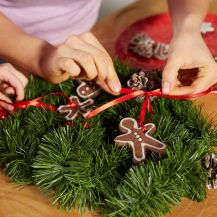 Mani di donna e bimba decorano una ghirlanda con biscotti di Natale al Nesquik