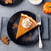 fetta di torta di zucca su piatto nero con panna montata