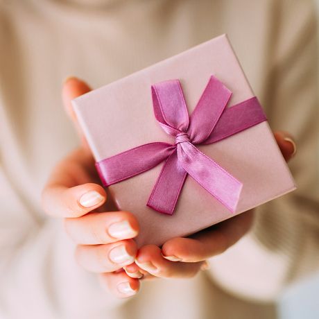 Mani femminili mantengono una scatola regalo con fiocco rosa