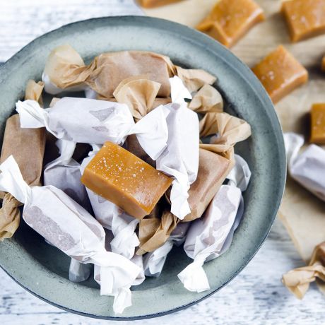 Caramelle mou su piatto su piatto grigio incartate o su tagliere bianco