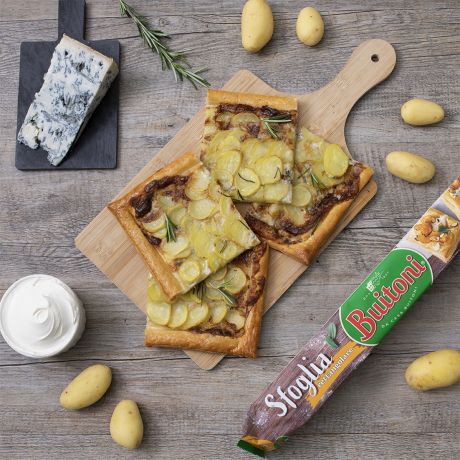 Sfogliata di patate su tagliere di legno con confezione di sfoglia Buitoni accanto