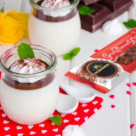 2 bicchieri di panna cotta con crema al cioccolato sul tavolo e Gran Blocco Perugina accanto