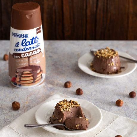 2 porzioni di panna cotta al cacao sul tavolo con latte condensato al cacao Nestlé accanto