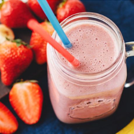 Smoothie alla frutta circondato da fragole