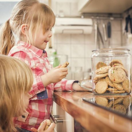due bambine prendono biscotti secchi da un vaso di vetro