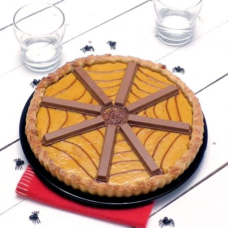 Kitkat Halloween Pie su tavola bianca con accanto ragnetti neri e bicchieri di vetro 