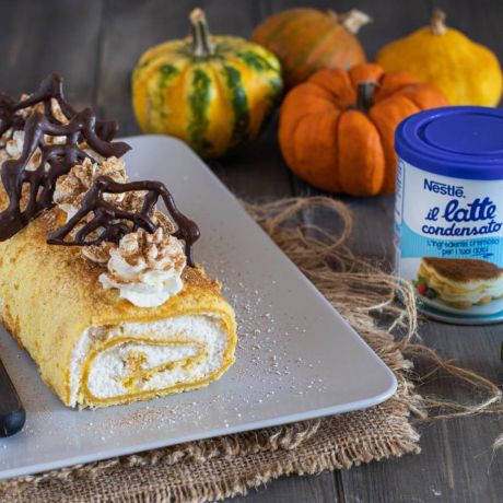 Rotolo alla zucca con decorazioni di halloween di cioccolato, barattolo de il latte condensato e zucche come decorazione nello sfondo