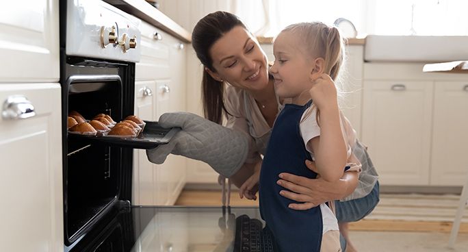 Donna insieme alla figlia cucina dei dolci nel forno 