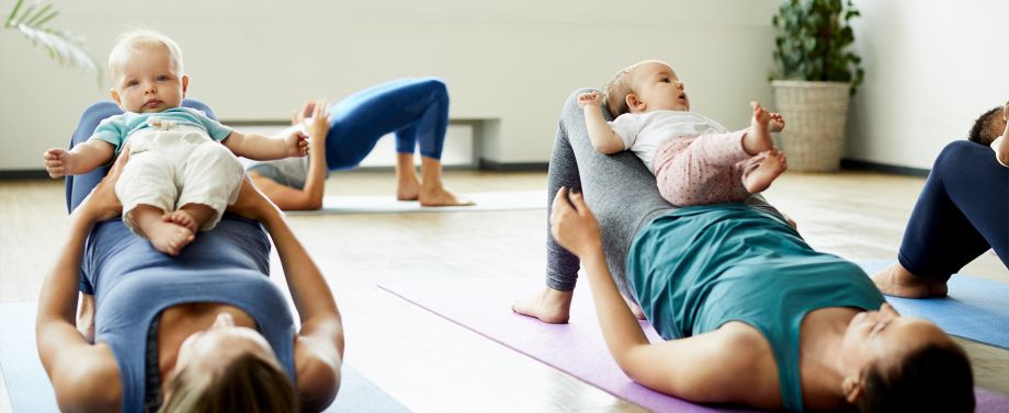 donne fanno ginnastica post parto a terra con bambini sul grembo