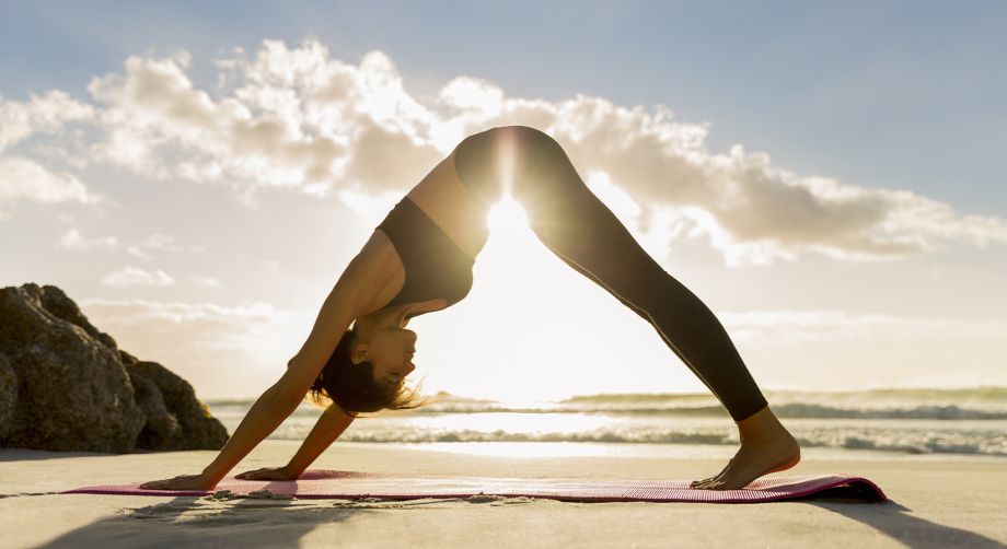 Ragazza che fa yoga in riva al mare